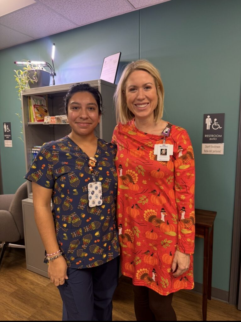 Abby y su asistente médico, de pie juntas.