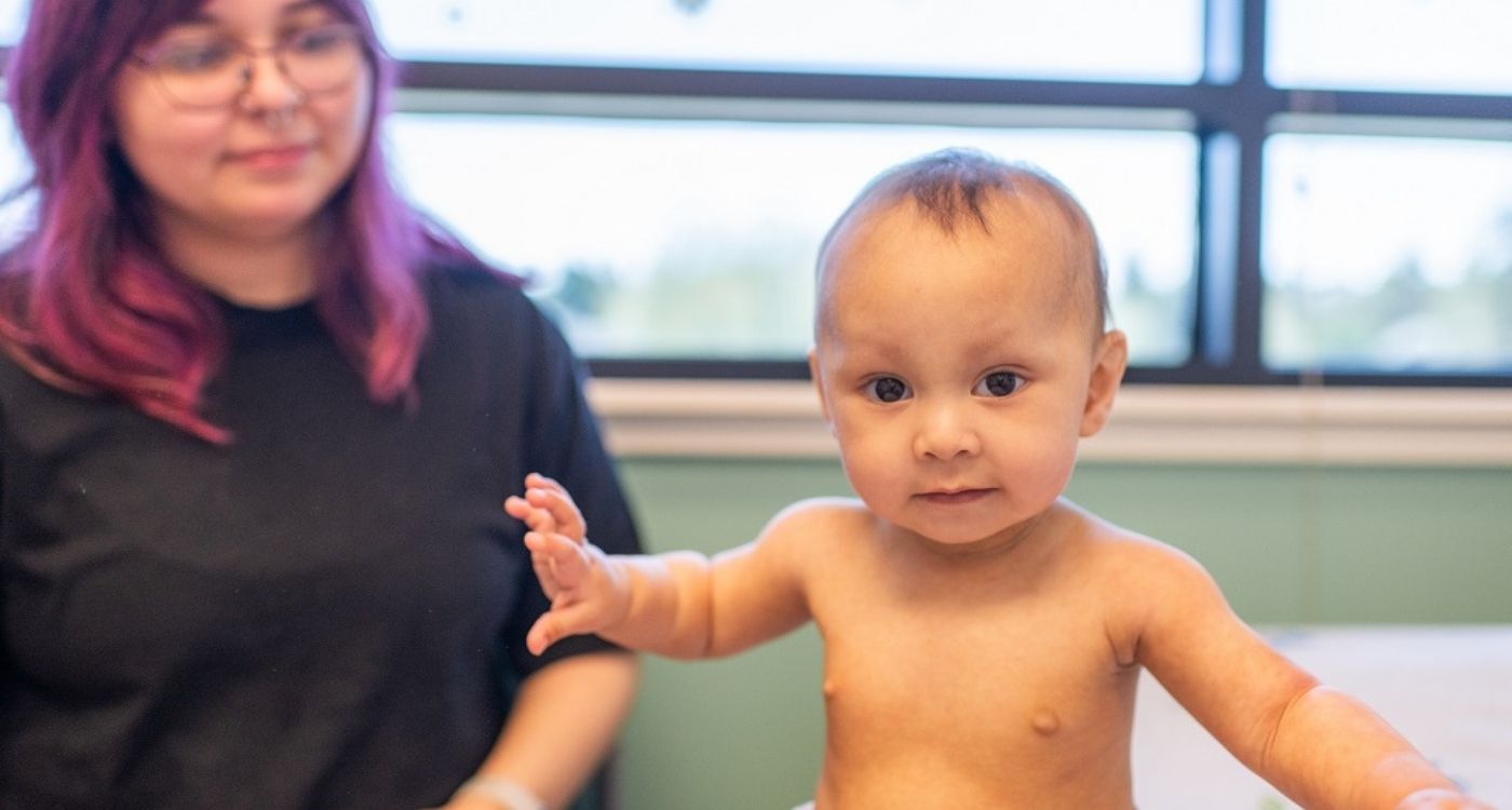 A baby sitting on an exam table.