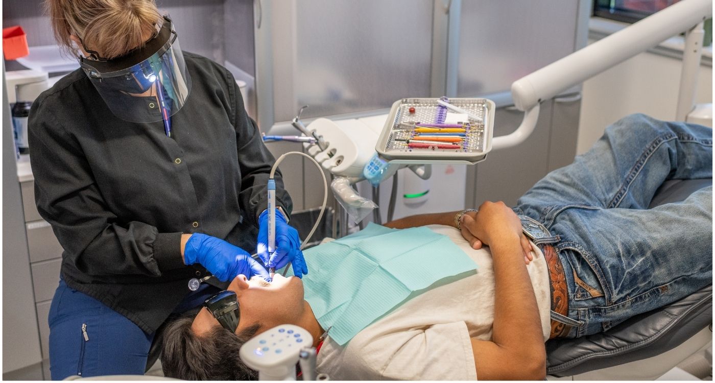 A dental hygienist cleaning a patient's teeth.