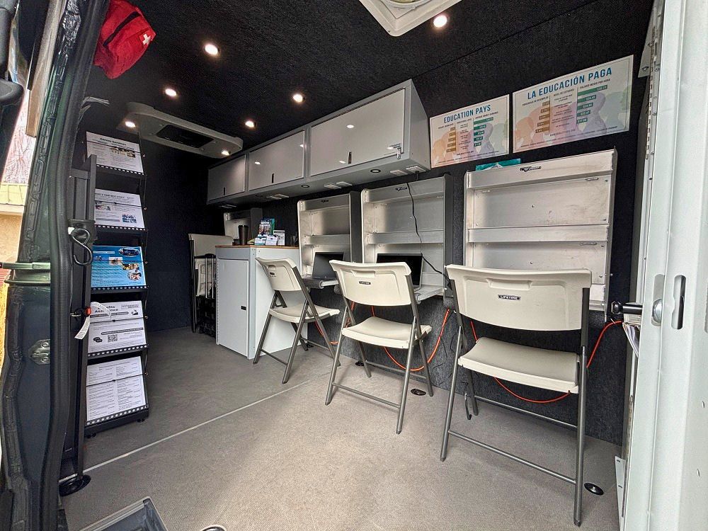 Interior of the Mobile Employment Resource Van with three computer workstations, chairs, storage cabinets and job training materials available for community members seeking employment support.