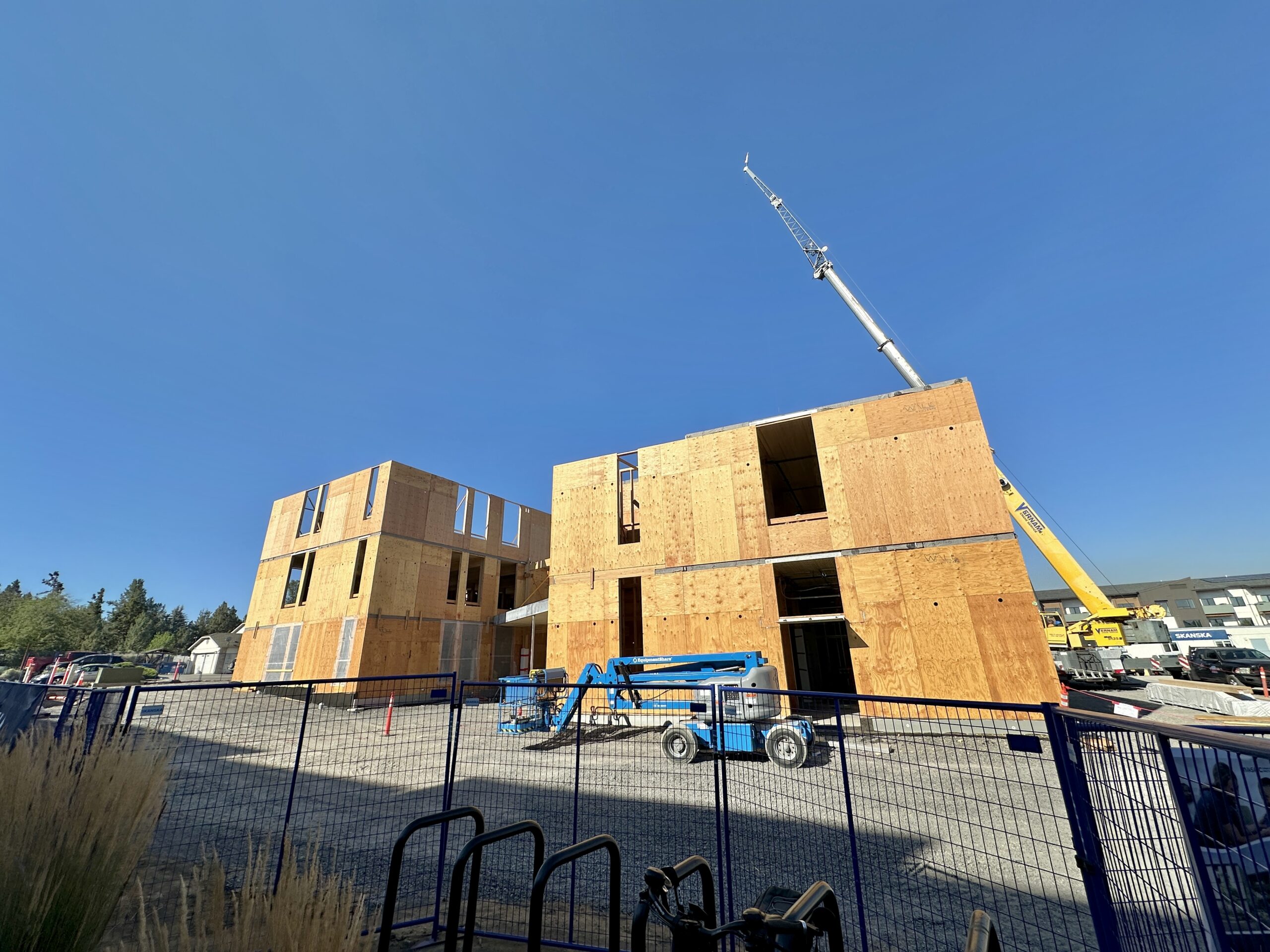Construction of Mosaic’s new Conners Campus building, showing the wood-framed structure with a crane and construction equipment on site.