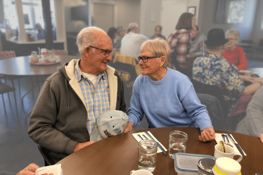 Older couple looking at one another affectionately during a community lunch.